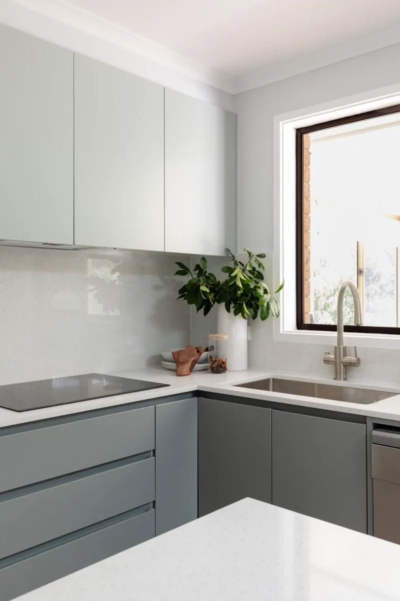 Belconnen kitchen with grey handleless cabinetry, a glass splashback and a window above the sink