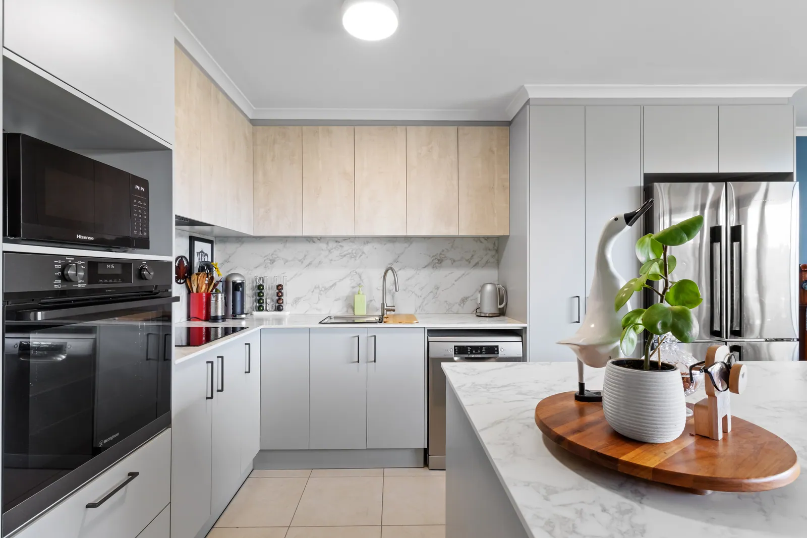 Bruce kitchen with light grey cabinetry, timber-look overheads and a stone-look benchtop