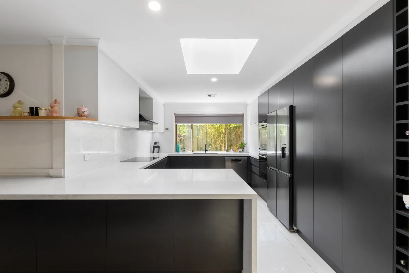 Calwell kitchen with black handleless cabinetry, white benchtops and a skylight above