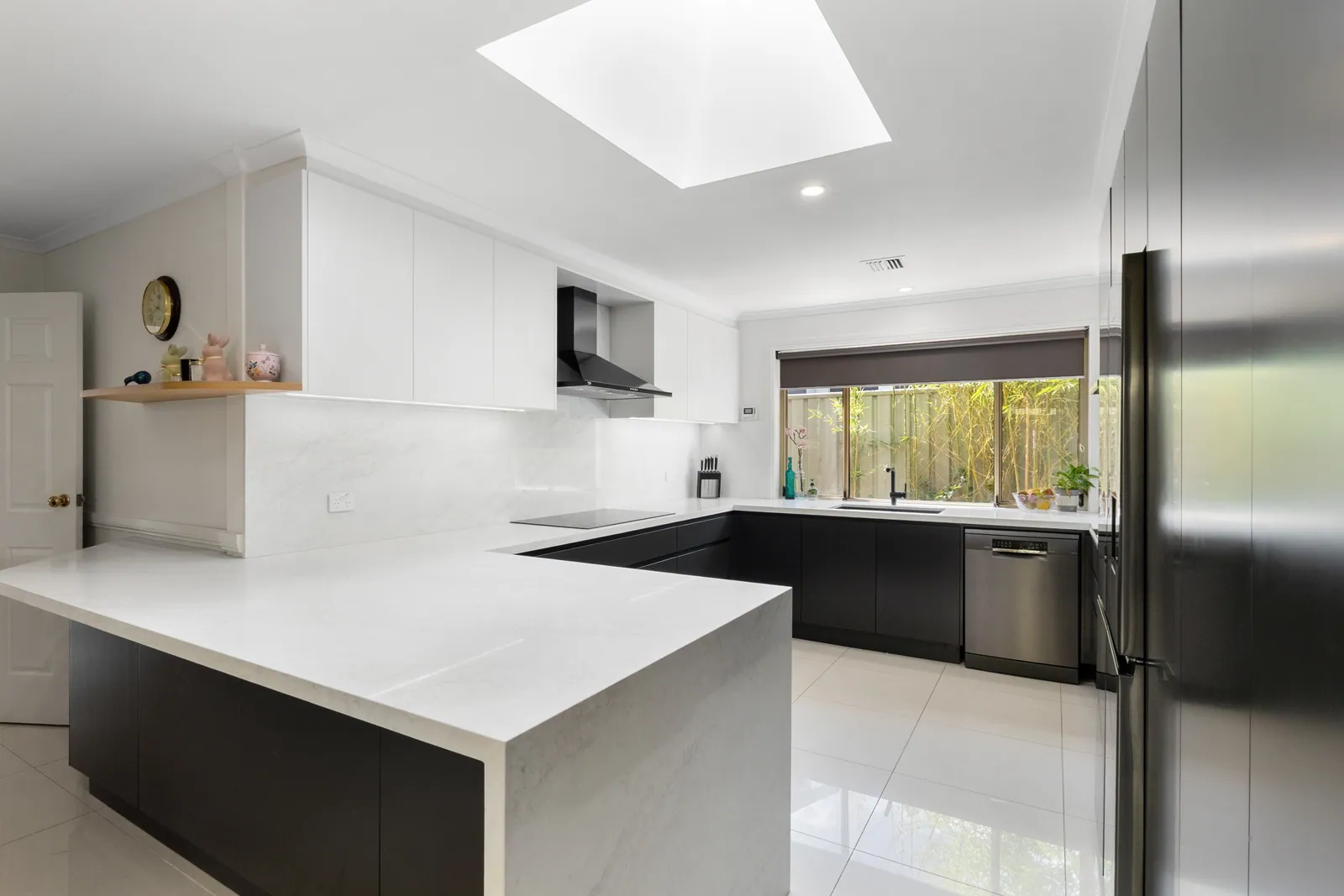 White benchtops wrapping the black Calwell cabinetry beneath a skylight