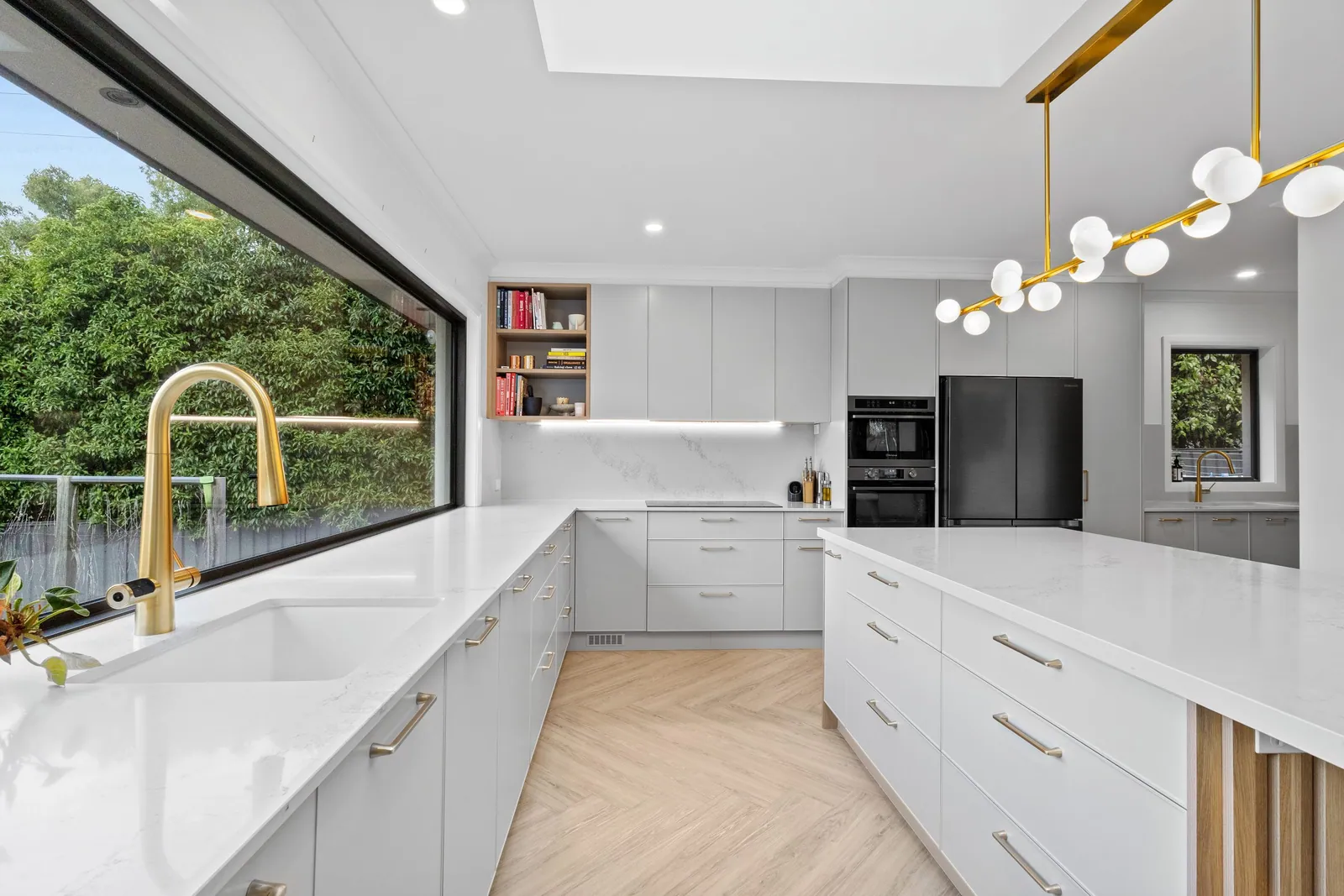 Chapman kitchen with white cabinetry, brass tapware and a window looking over the garden