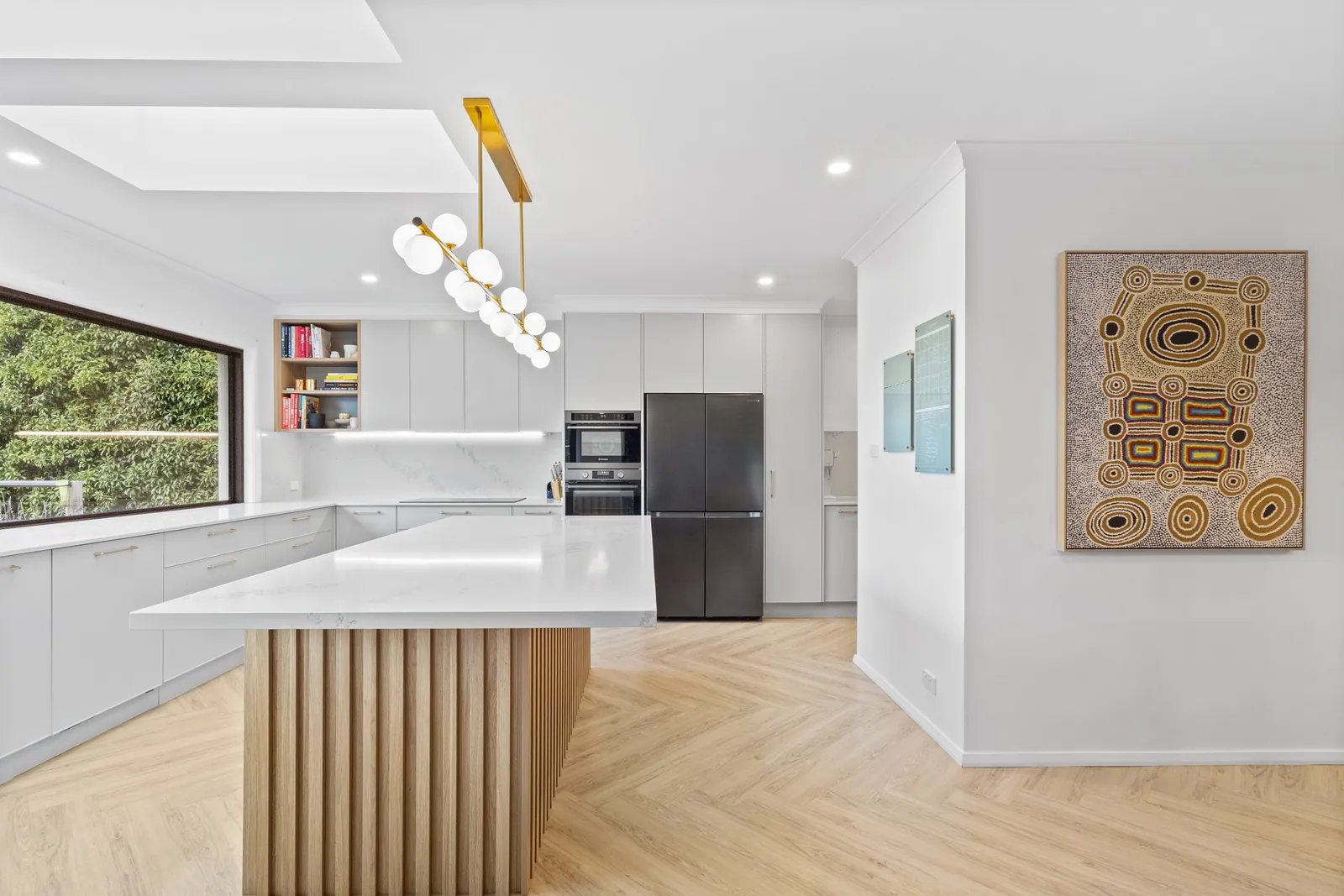 White bench runs and fluted timber island in the open Chapman kitchen