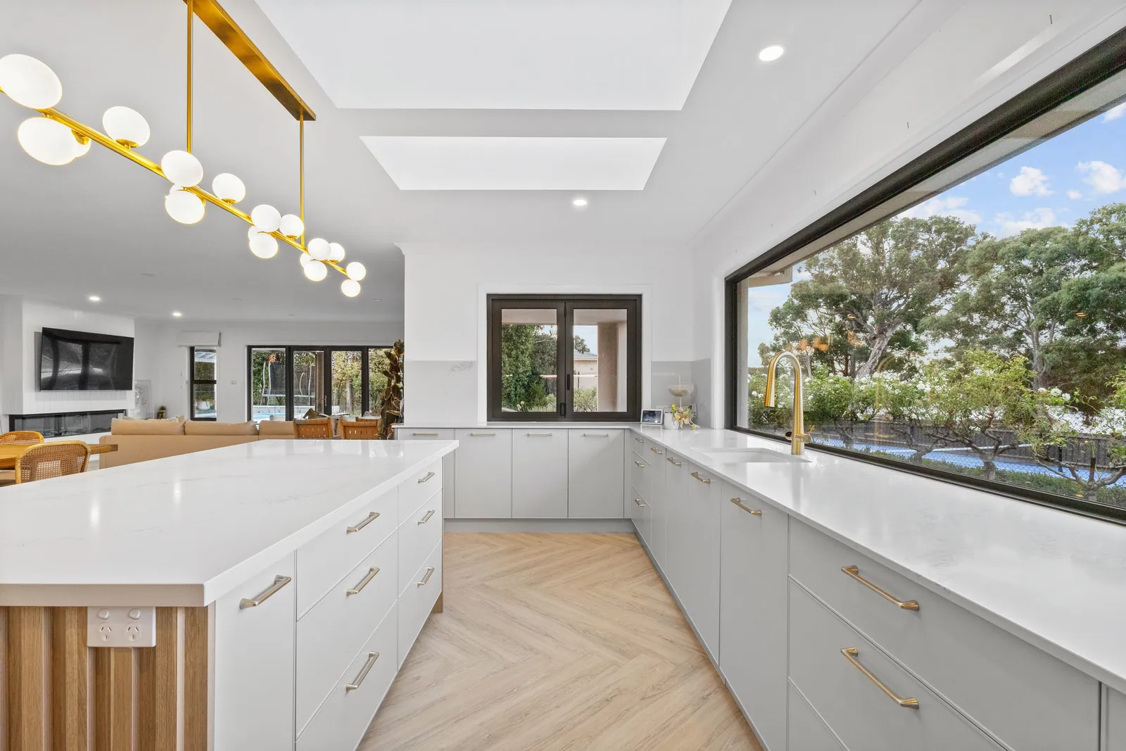 Chapman kitchen with white cabinetry, brass handles and a picture window
