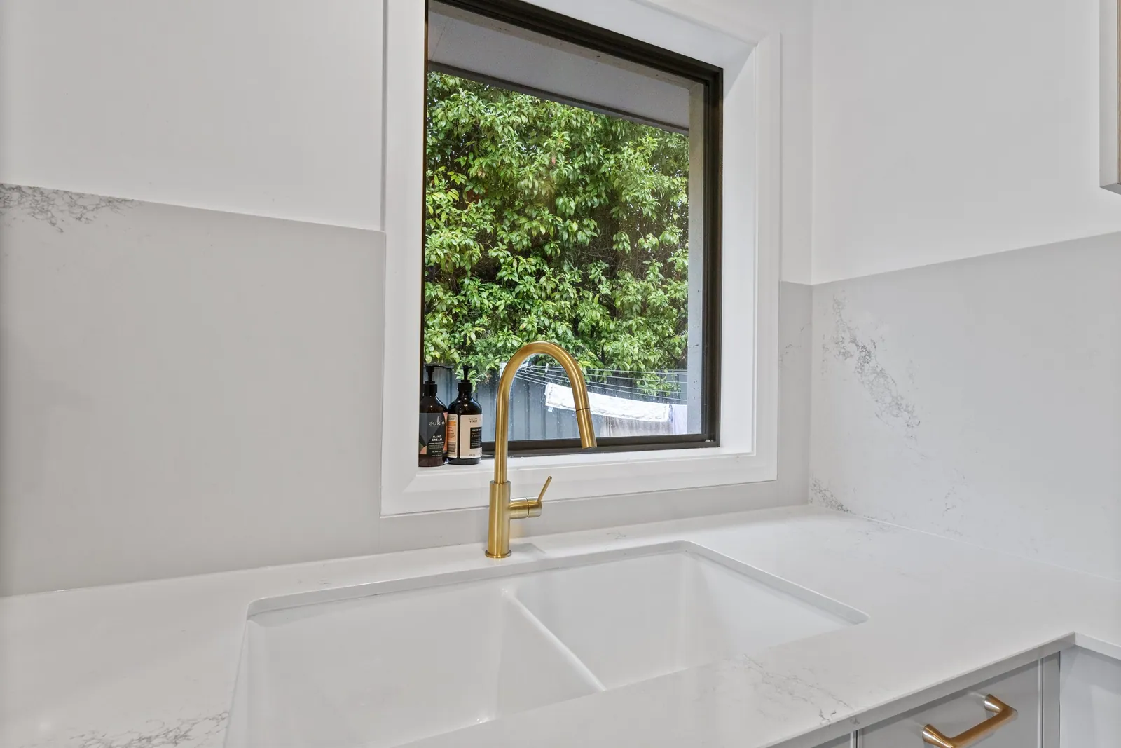 Stone-look benchtop, brass tapware and window in the Chapman kitchen