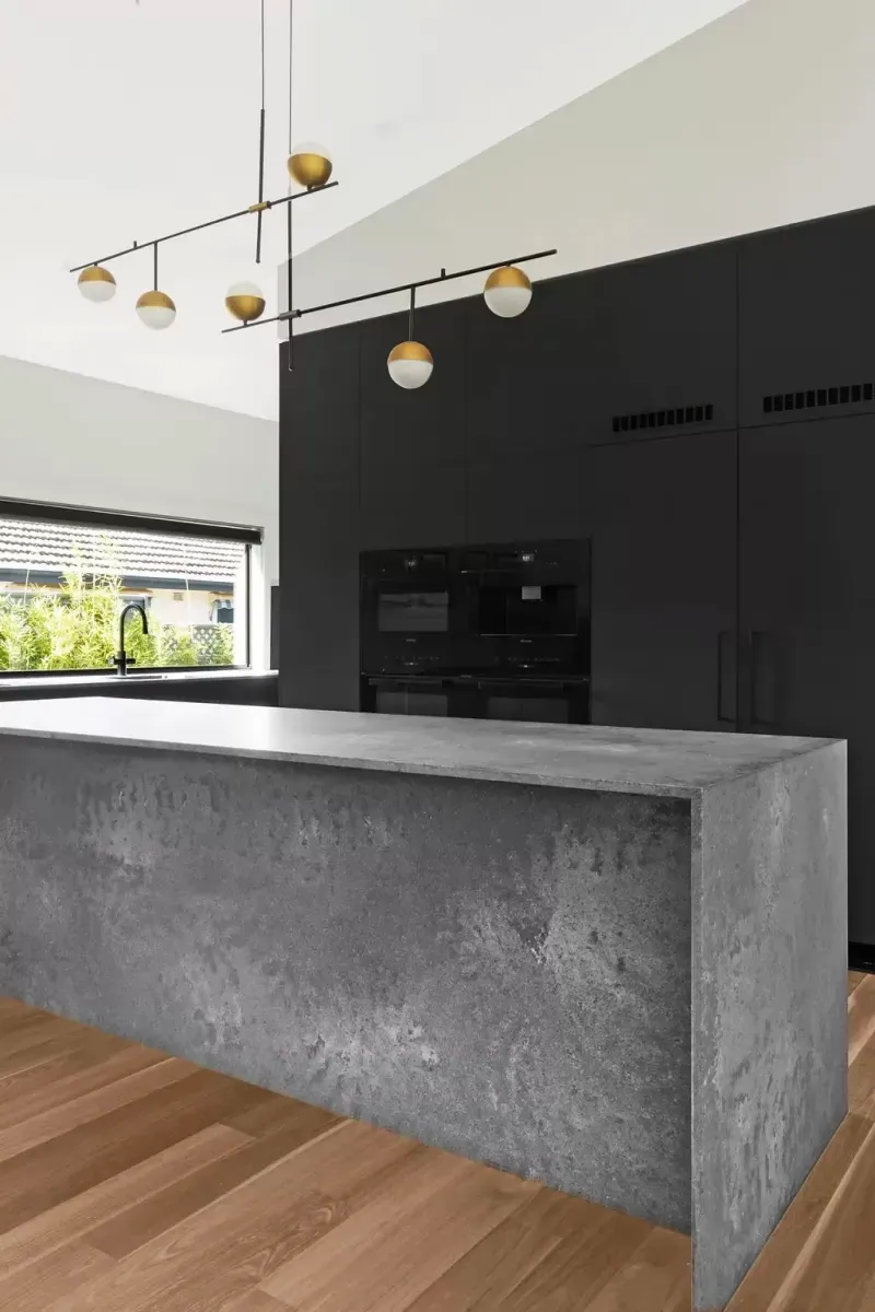 Black appliance cabinetry behind the concrete-look island in the Deakin kitchen