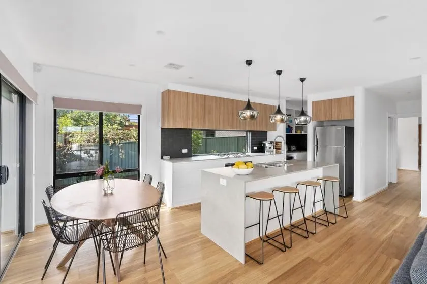 Flynn kitchen with white cabinetry, timber overheads and a dining table alongside