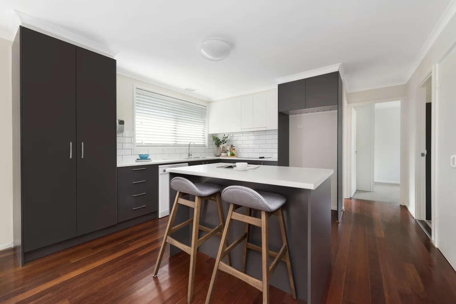 Giralang kitchen with dark grey cabinetry, white benchtops and an island with seating