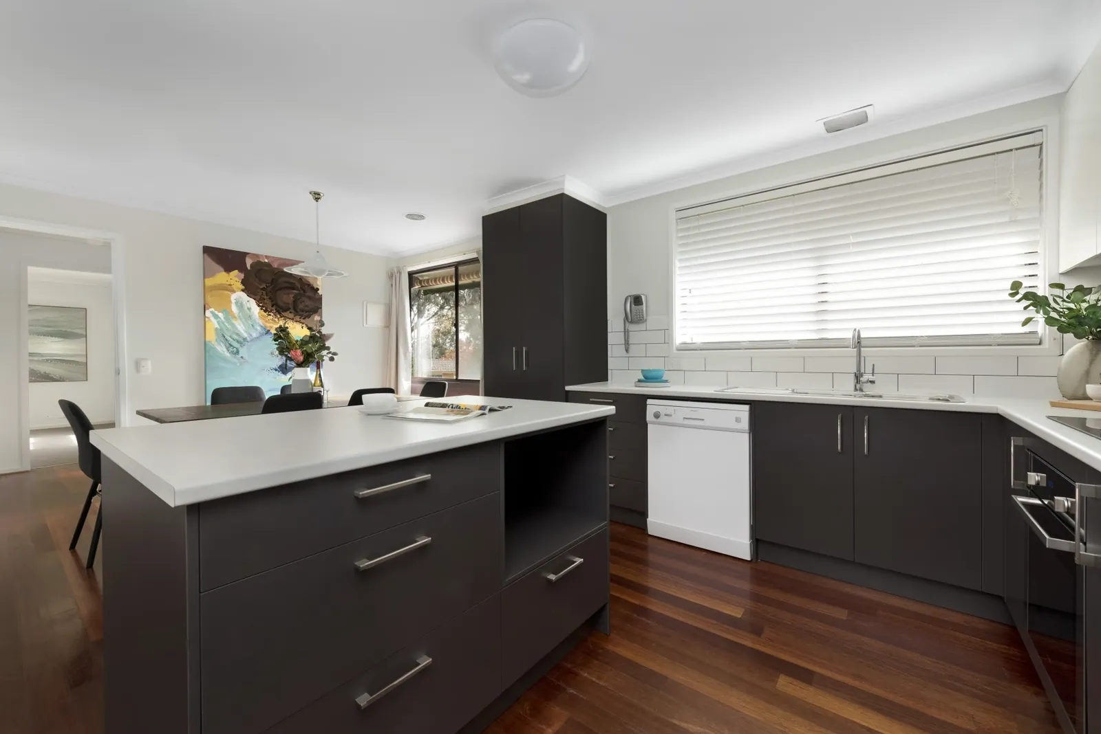 Giralang island bench and dark grey cabinetry with a subway tiled splashback