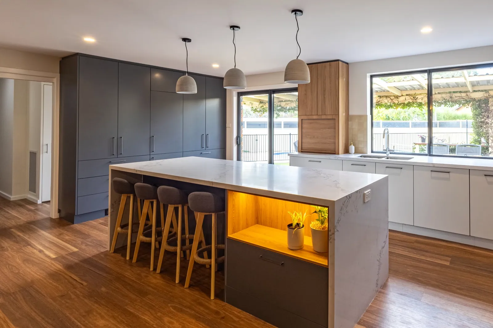 Kaleen kitchen island with timber stools, timbergrain overhead cabinetry and dark grey joinery