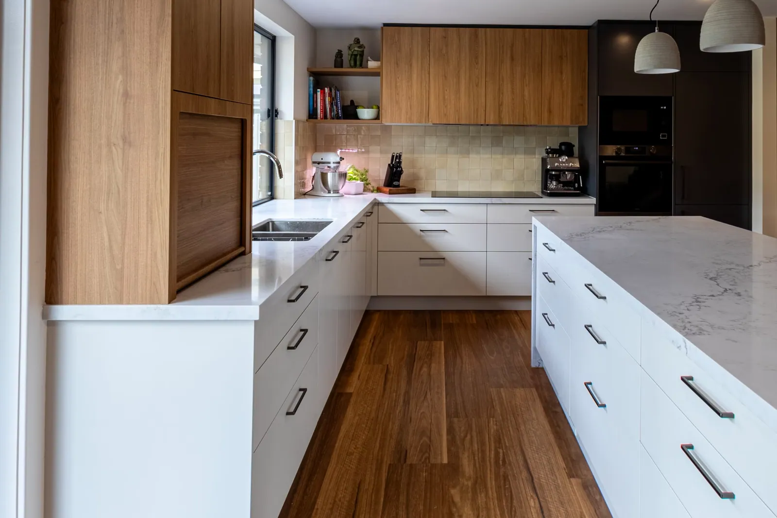 White cabinetry and drawer banks running around the Kaleen kitchen with timbergrain overheads