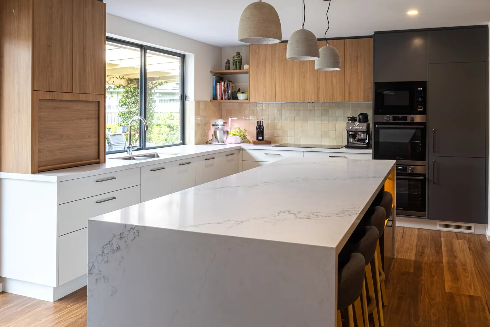 Kaleen kitchen looking across the island to the window bench and dark grey oven tower