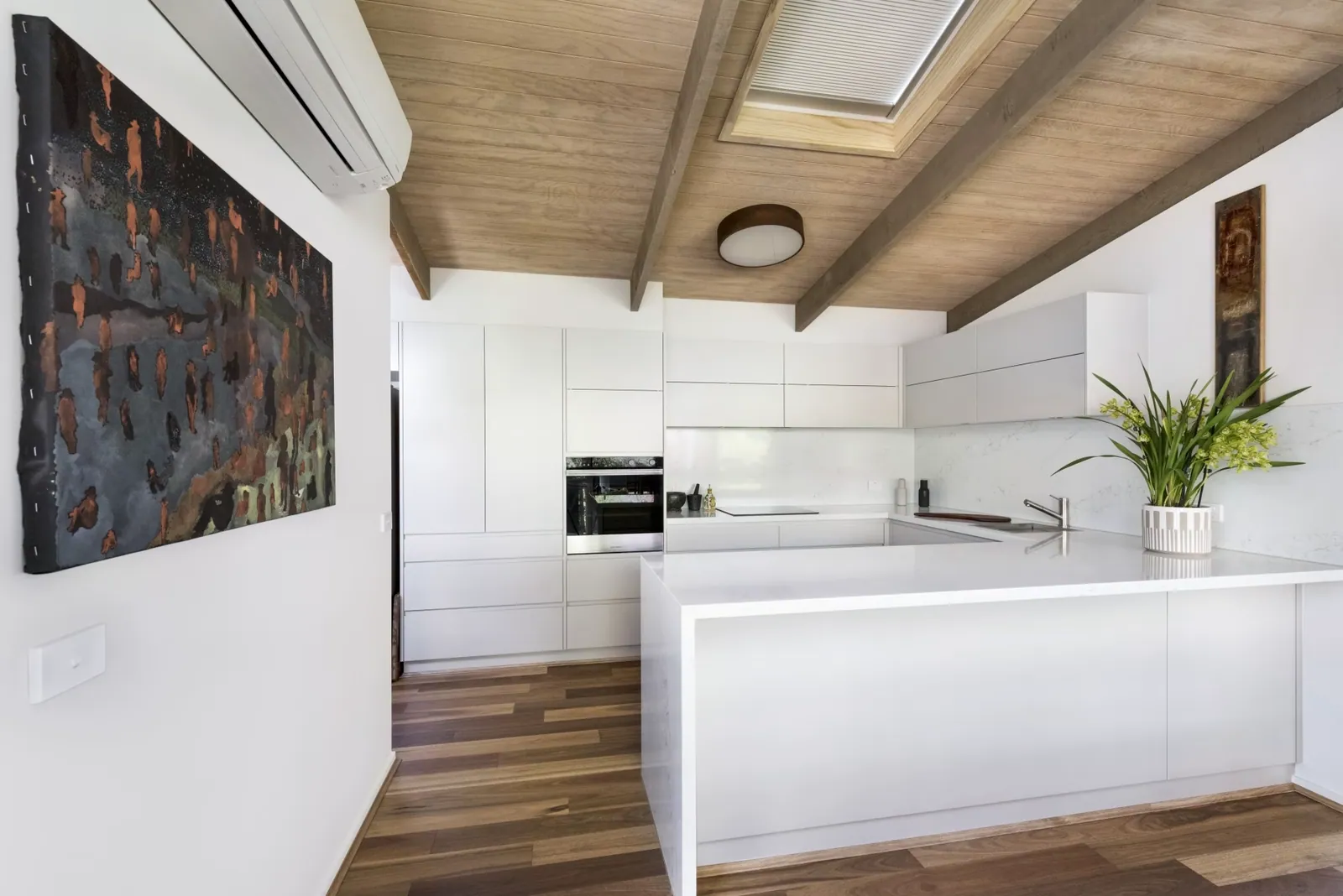 Mawson kitchen with white cabinetry beneath a timber-lined raked ceiling