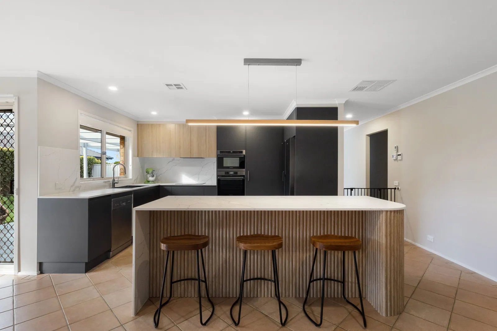 Fluted timber island with stools in the black Nicholls kitchen