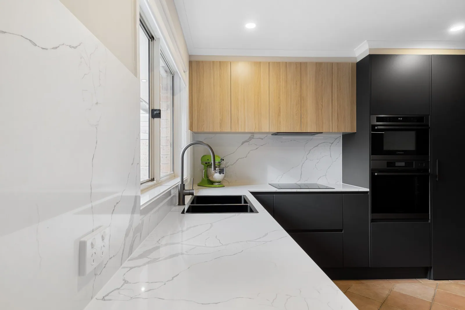 Stone-look splashback, black tapware and timber overheads in the Nicholls kitchen