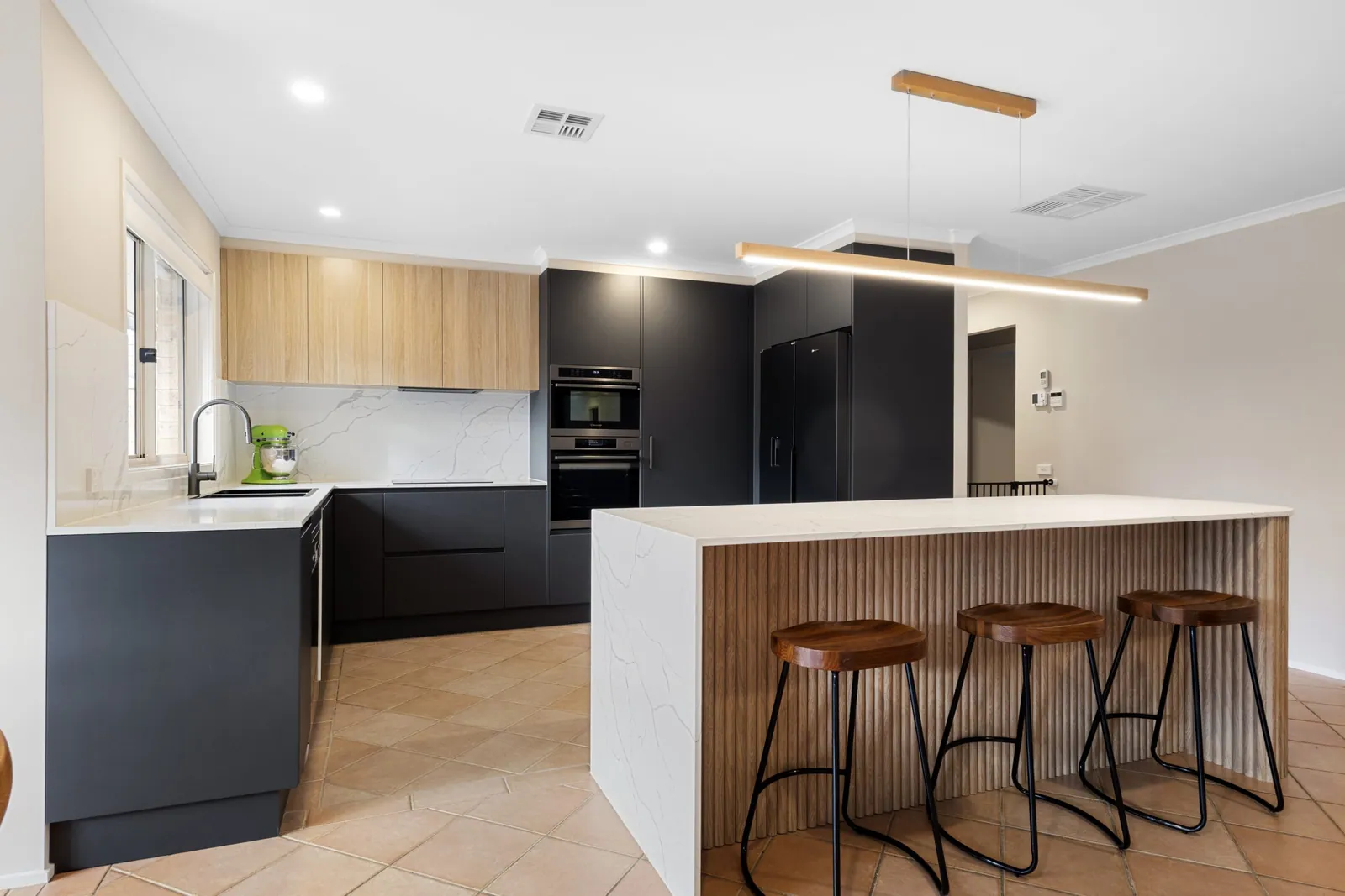 Black cabinetry and timber overheads either side of the Nicholls kitchen island