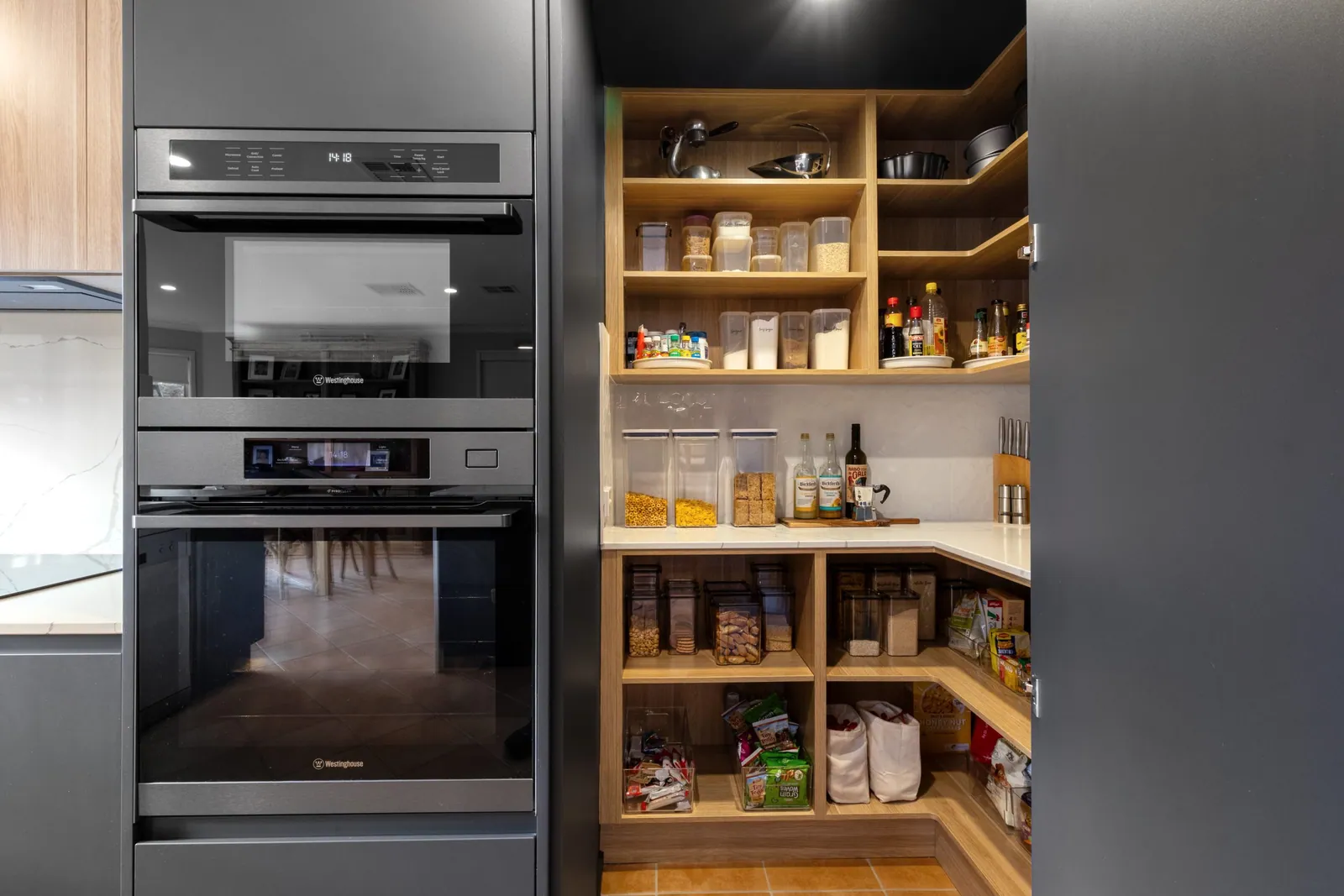 Timber-shelved walk-in pantry beside the black Nicholls cabinetry