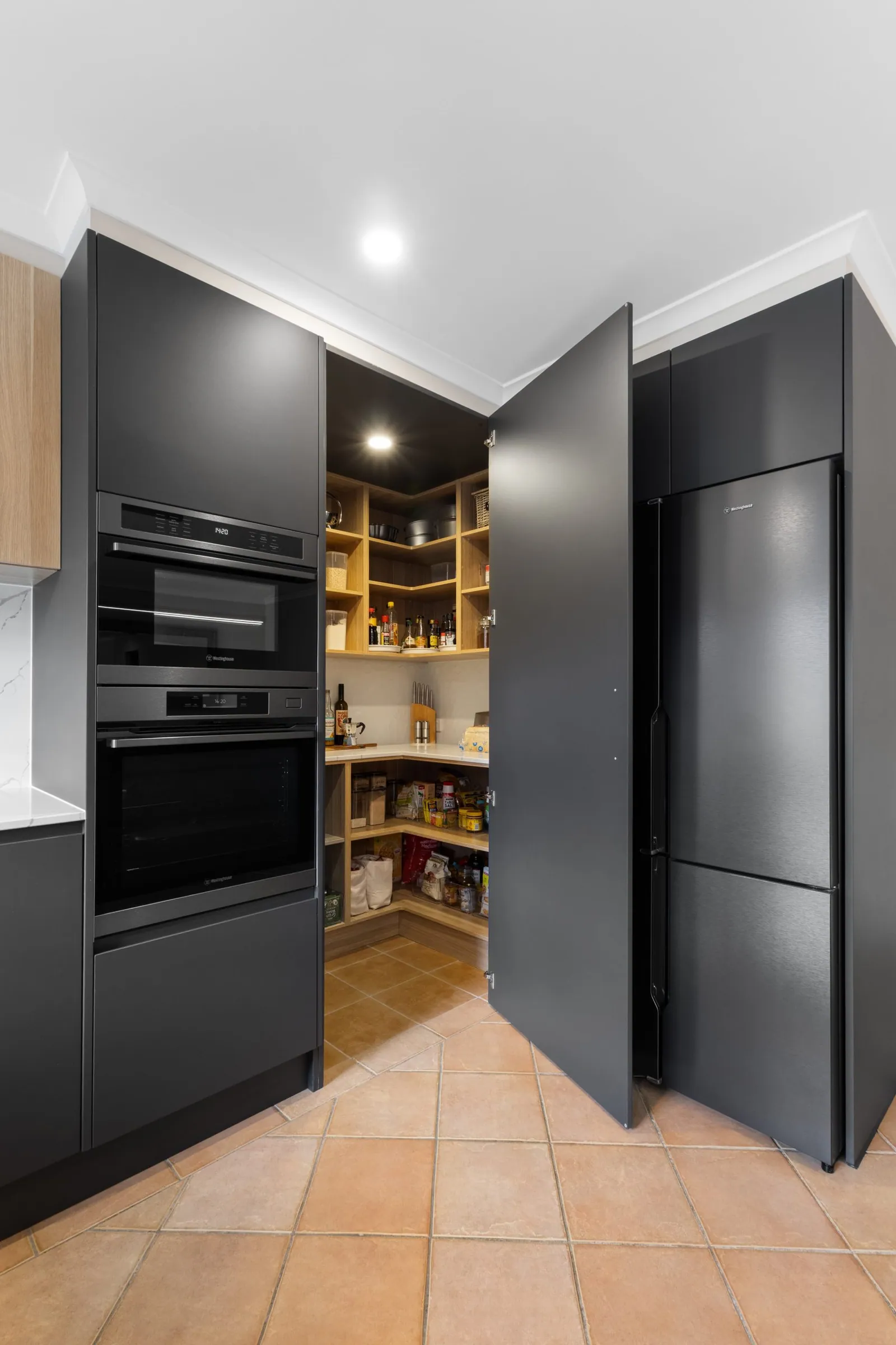 Pantry door open beside the black cabinetry in the Nicholls kitchen