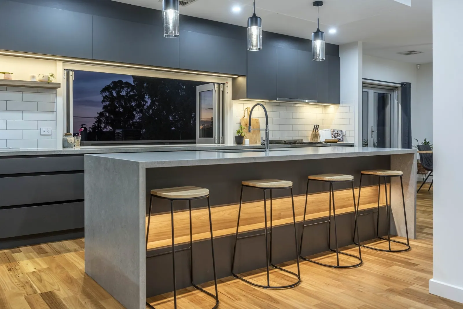 Weetangera kitchen with dark grey cabinetry, a stone-look island and bar seating